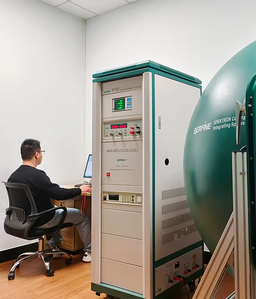 Engineer working at computer connected to integrating sphere for LED optical testing
