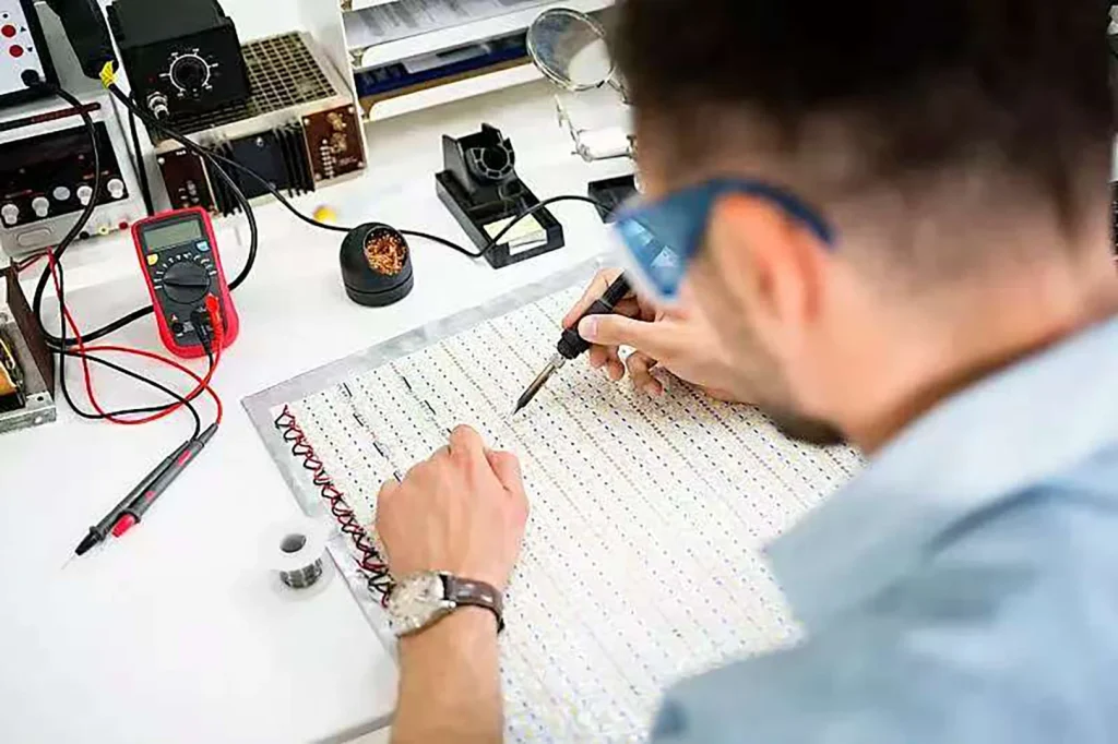 Engineer performing precision soldering or measurement on LED board